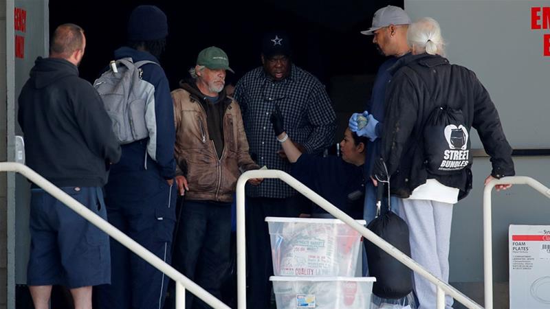 Homeless people arrive at the San Deigo convention centre, now being used to house some of the city's homeless population during the coronavirus pandemic [Mike Blake/Reuters]
